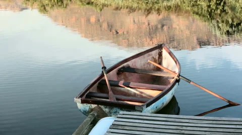 Slow panning shot across battered, old, abandoned rowboat at a dock Stock Footage 54226403