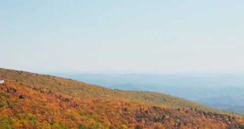 Slow panning shot of colorful Fall Autumn mountain trees with with cars driving Stock Footage 220528779