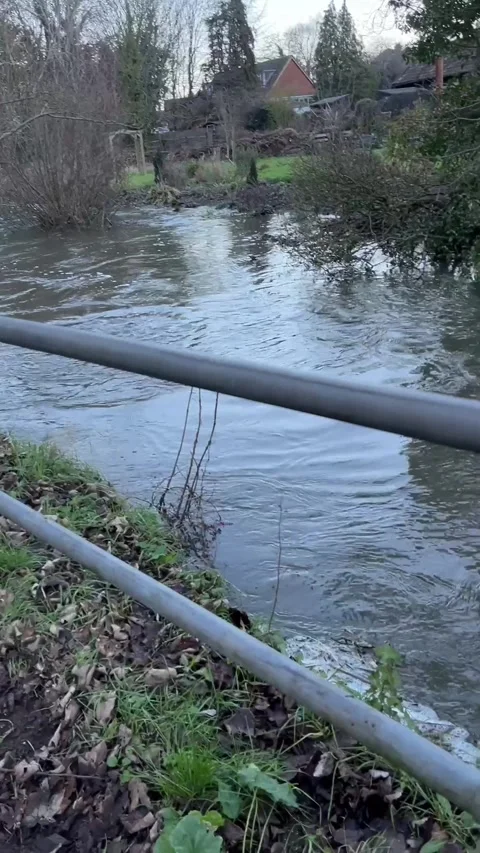 Slow panning shot of flooded river and submerged stone footbridge, England Stock Footage 326237389