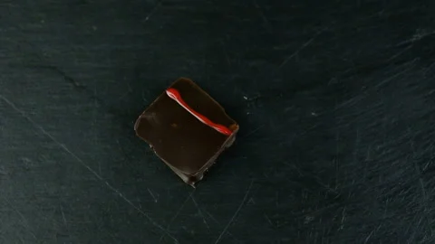 Slow panorama on small square chocolate candy on black kitchen table Stockbeeldmateriaal 103855661