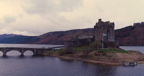 Slow pass of Eilean Donan Castle, with Scottish flag flying drone aerial 4K Stock Footage 104584208