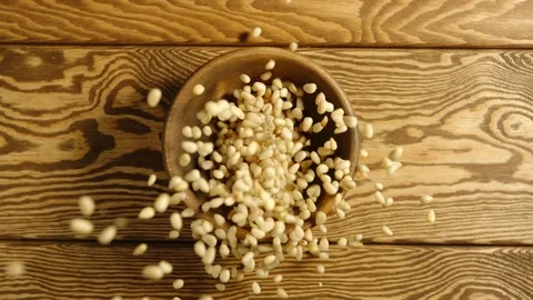 SLOW: Pine kernels fall into a wooden dish on a table - Top view Stock Footage 96193156