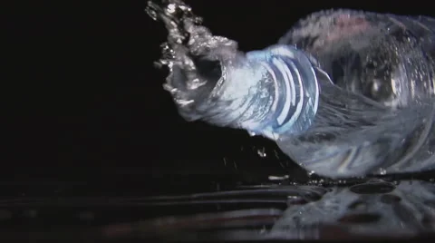 SLOW: A plastic bottle falls on a black table and water pours from it Stock Footage 64209927