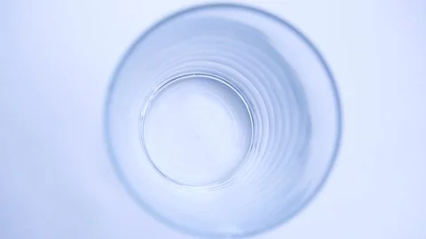 Slow process of pouring yellow orange in transparent glass on white background. Stock Footage 90060358