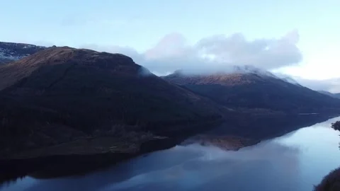 Slow Pull Back High Over Calm Waters of Scottish Loch With Mountains and Clouds Stock Footage 277731226