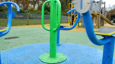 Slow pull back shot of merry go round spinning in empty play area. Stock Footage 98713596
