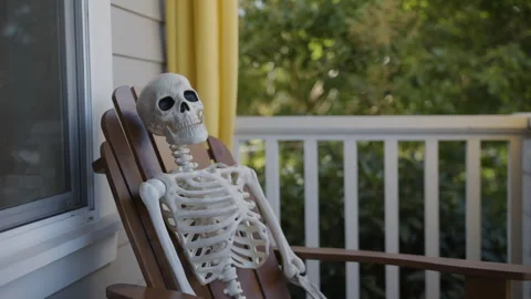 Slow Pull Back from Skeleton in Adirondack Chair on Craftsman Porch on Sunny Day Stock Footage 319820186