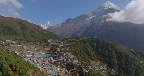 Slow pull-out drone shot of Namche Bazaar town framing Ama Dablam and Thamserku Stockbeeldmateriaal 337394204
