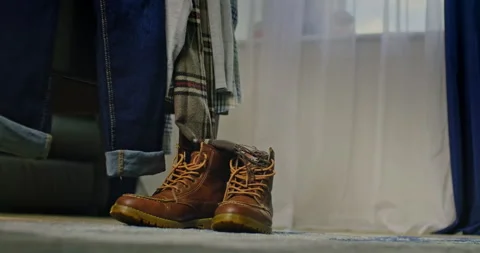 Slow push in to autumn fall boots and clothes hanging from the edge Stock Footage 204046796
