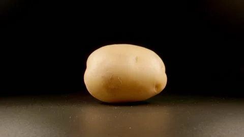 SLOW: Raw potato rolls on black isolated surface Видео 201855763