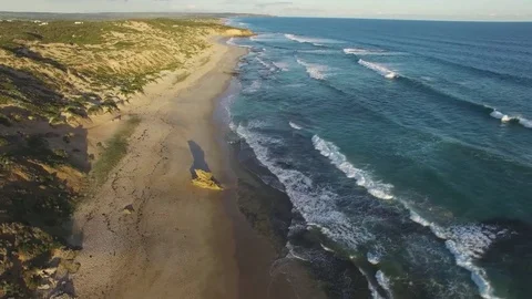 Slow rise above ocean beach coastline and big waves at sunset. Mornington Pen Stock Footage 77760089