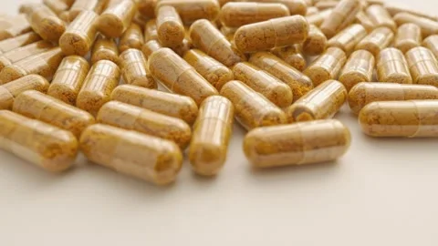 Slow rotation of curcumin capsules on the background of the production of Stock Footage 284711472