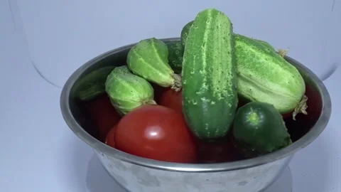 Slow rotation of fresh cucumbers and tomatoes in metal bowl Stock Footage 337770680