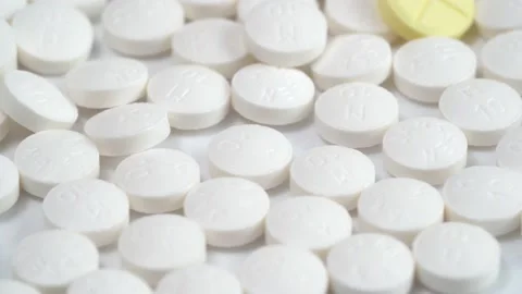 Slow rotation of a large group of white pills and one yellow pill on the middle Stock Footage 140291465