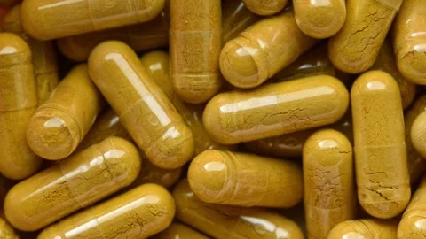 Slow rotation reveals close macro pattern of yellow herbal capsules for Stock Footage 335745044