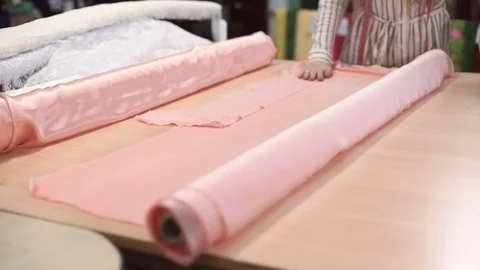 Slow shooting fabric store worker unwraps pink roll atlas tissue Stock Footage 73286664