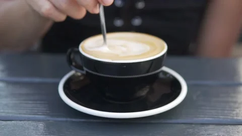 Slow shooting, a woman's hand stirs the cappuccino with a spoon Stock Footage 220958677