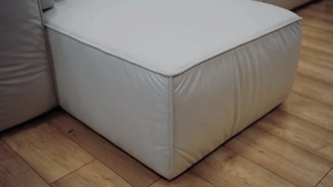Slow shot to a piece of white sofa on a brown floor. 4k video. Stock Footage 231688752