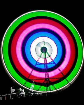 Slow shutter image of a rotating Giant Colorful Ferris wheel spinning at nigh Stock Photos