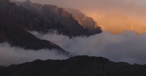 Slow sideways drone shot of dramatic clouds rolling over mountain ridges in Stock Footage 337392052