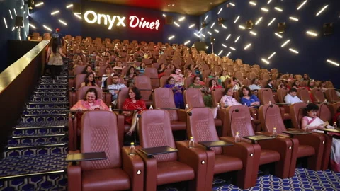 Slow sideways handheld track shot of Men and Women waiting to watch a film Stock Footage 137155235