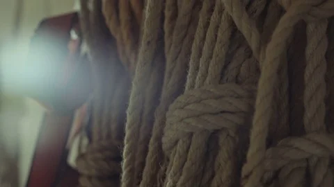 Slow slider shot of old craft ropes while a flare fills the screen on the left Stock Footage 85215820