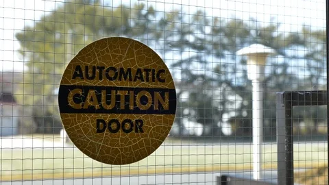 Slow slider towards Automatic Caution Door label on glass door Stock Footage 125037597