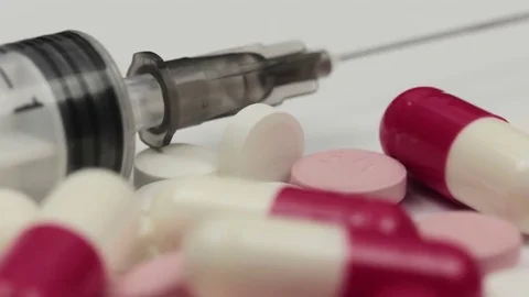 Slow smooth macro slide over different multicolored pills and a syringe Vidéo 72404915