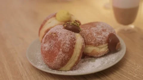 Slow spinning shot of three filled doughnuts on plate in warm home setting Stock Footage 321019994