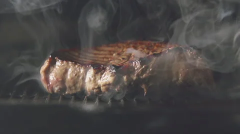 SLOW: A steak of meat is cooking on a grill Stock Footage