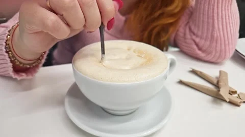 Slow stirring of sugar in latte in white ceramic cup by girl's hand 스톡 동영상 243203567