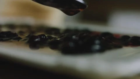 Slow syrup drizzle landing over blackberries at table level Stock Footage 342127579