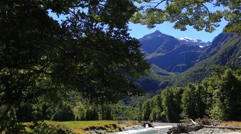 Slow tilt from distant mountains to swift running river below Stock Footage 34342134