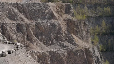 Slow tilt down to a deep hole in a stoney lime factory quarry with roads Stock Footage 183100069