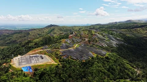 Slow tilt down reveals vast solar arrays across lush Philippine mountain hills Stock Footage 342178822