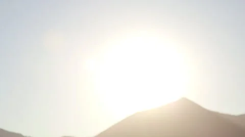 Slow Tilt Down from Sky to Man Looking Towards the Sunset Over Mountains 動画素材 68723667