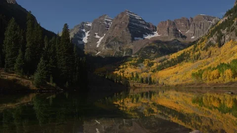 Slow tilt up from a reflection to the Maroon Bells peaks in Colorado in Autumn Stock Footage 119330145
