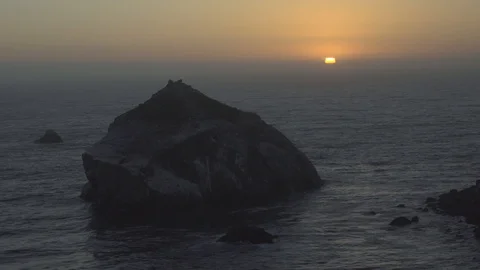 Slow Tilt to Reveal a Setting Sun Over the Ocean Stock Footage 101015747