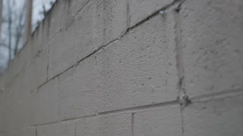 Slow tilt up of white brick wall in snow fall 動画素材 145196037