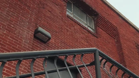 Slow Top to Bottom Pan of Metal Staircase Against Brick Wall Stock Footage 327328033