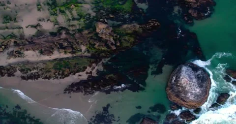 Slow top-down pan of waves breaking against rocks at the coast (aerial) Stock Footage 67647546