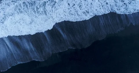 Slow tracking aerial of ocean waves on beach Stockbeeldmateriaal 79834366