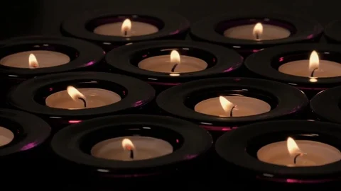 Slow tracking shot of flickering tealight candle flames Stock Footage 73954440