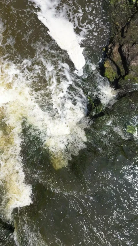 Slow vertical drone up over a small waterfall Video stock 246717542