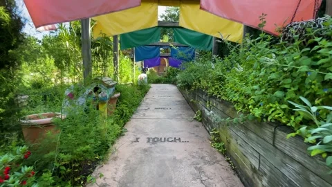 Slow walking shot down garden path through colored garden flags Stock Footage 239071084