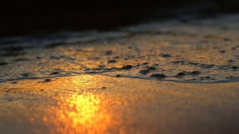 Slow waves on a beach at sunset with bokeh Stock Footage