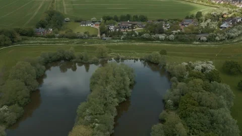 Slow wide flight over a tree lined lake with plush gardens passing over fish Stock Footage 297173716