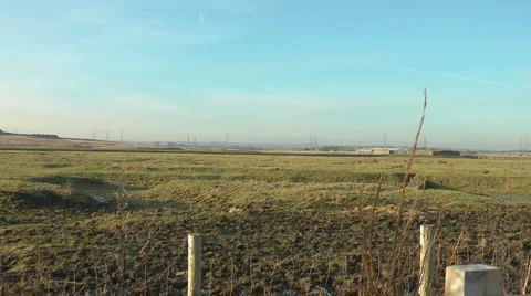 Slow zoom across fields to Electric Pylons in distance. Stock Footage 1047218