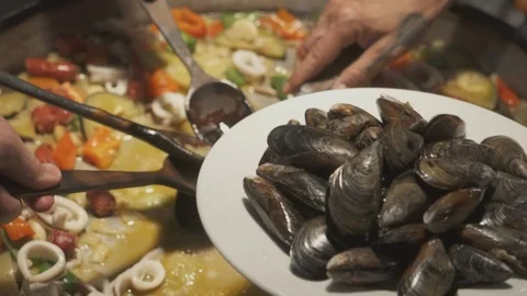 Slowly adding mussels to paella in a big pan Video stock 100393649