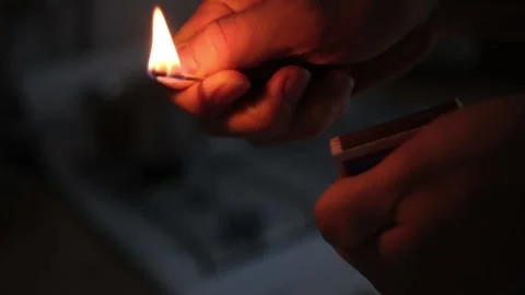 Slowly extinguish the match. Fire in the hand. Against the background of a blurr Stock Footage 147178713